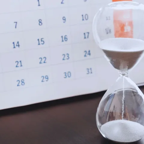 An hourglass beside a calendar, representing a treatment course compressed into fewer days