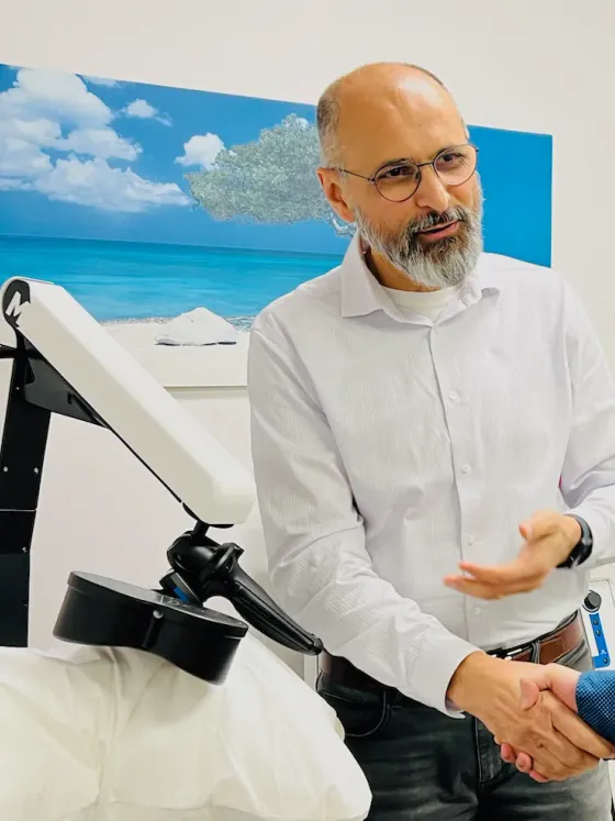 Dr. Nazarani next to TMS equipment explaining treatment to a patient